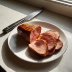 Sliced beef tenderloin recipes oven on a white plate with a knife, showcasing the perfectly cooked, juicy meat.