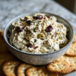 A bowl of creamy dirty martini dip topped with olives and served with crackers.
