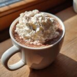 A mug of French hot chocolate topped with a generous dollop of whipped cream and chocolate shavings.