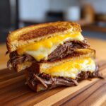Stacked grilled cheese sandwich made with leftover roast beef recipes and melted cheese on toasted bread.