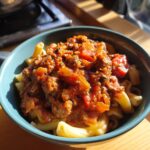 Bowl of pasta topped with a rich tomato sauce featuring ground sausage recipes.