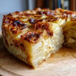 Close-up of homemade scalloped potatoes with a golden-brown crust, served on a wooden board.