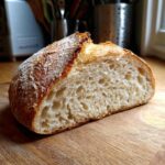 A close-up of a sliced sourdough bread loaf, showcasing the airy texture from an active sourdough starter.