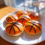 A plate of homemade basketball cookies decorated with orange icing and black lines to resemble basketballs.