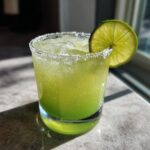 Icy best margarita recipe in a salted glass, garnished with a fresh lime slice.