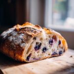 A close-up of a sliced blueberry sourdough bread loaf, showing the blueberries and airy crumb.