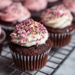 Close-up of chocolate wedding cupcakes decorated with white frosting and colorful sprinkles.