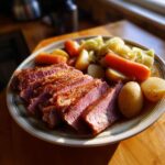 A plate of sliced corned beef recipes slow cooker style, served with carrots, potatoes, and cabbage.