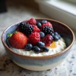 A bowl of cottage cheese recipes topped with fresh berries like strawberries, blueberries, raspberries, and blackberries.