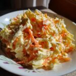 Close-up of coleslaw featuring cabbage, carrots, and a creamy coleslaw dressing on a decorative plate.