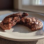 Two halves of a Healthy Chocolate Cookie on a plate, showing melted chocolate chips.