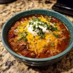 A bowl of Instant Pot White Chili topped with sour cream, shredded cheese, and fresh parsley.