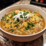 A bowl of Instant Pot White Chili topped with shredded cheese, sour cream, and cilantro.