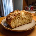 A slice of golden brown Irish soda bread on a plate, showing the crumb texture and crust.