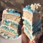 A slice of layered Pisces birthday cake with white frosting and blue decorations.