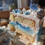 A slice of Pisces birthday cake with white frosting, blue decorations, and a fish topper.