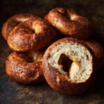 A stack of freshly baked protein bagels, one sliced open to show the texture.