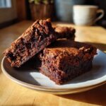 Three sourdough discard brownies stacked on a plate, showcasing their rich, fudgy texture.