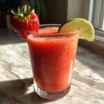 A vibrant strawberry daiquiri recipe, garnished with a fresh strawberry and lime wedge.