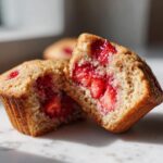 Close-up of a strawberry muffin cut in half, revealing fresh strawberries inside. Delicious strawberry muffins.