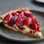 A slice of strawberry tart, showcasing a buttery crust, creamy filling, and fresh strawberries. One of our favorite strawberry recipes.