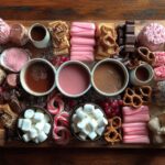 Overhead view of a hot chocolate charcuterie board with various toppings and hot chocolate mugs.